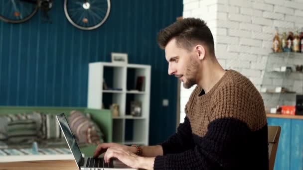 Homem bonito sorte trabalhando em um laptop, olhando para a câmera e sorrindo . — Vídeo de Stock