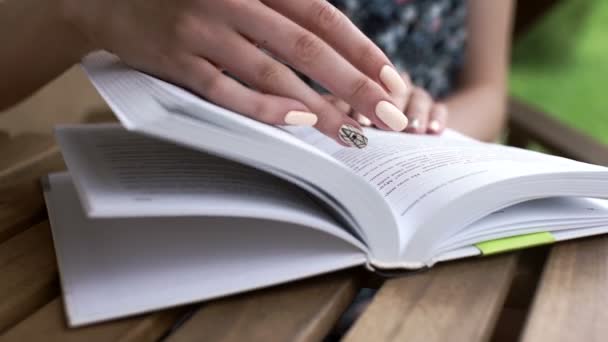 Крупним планом жіноча рука читає книгу на відкритому повітрі — стокове відео