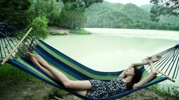 Woman relaxes in hammock, swaying gently, in wood — Stock Video