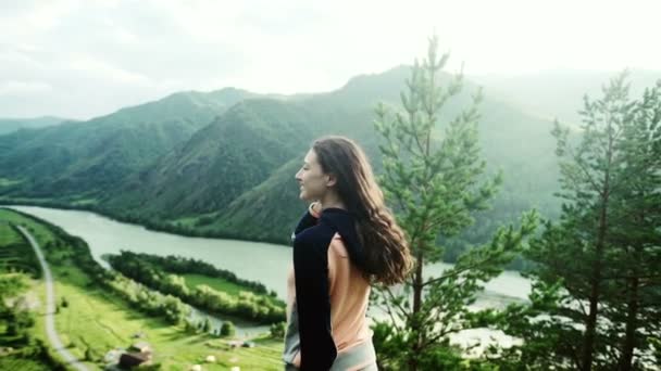 Νεαρή γυναίκα χαρούμενη αυξάνοντας τα χέρια της επάνω στο όμορφο βουνό. αργή κίνηση — Αρχείο Βίντεο