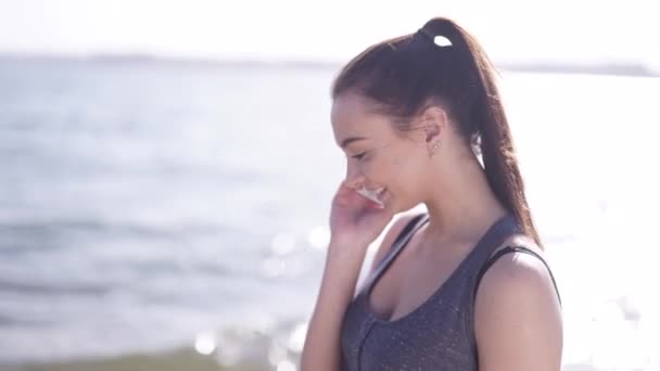 Joven atlética hablando por teléfono en una playa — Vídeos de Stock