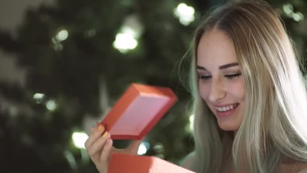 Krásy dívka otevírá Vánoční dárková krabička s a hledí do kamery