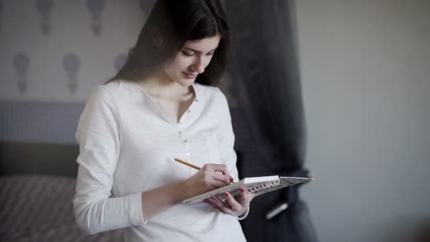 Schönes Mädchen am Morgen, das Notizen ins Tagebuch schreibt — Stockvideo