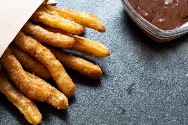 Çikolatalı Churro çubuğu siyah granit tahtada.