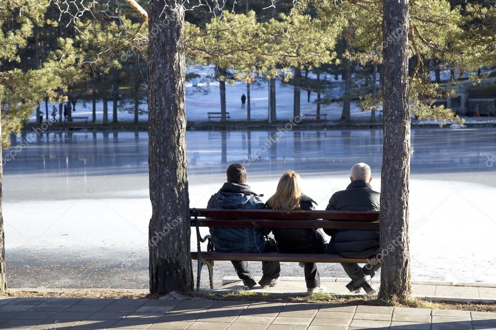 Three people sitting on a wooden bench