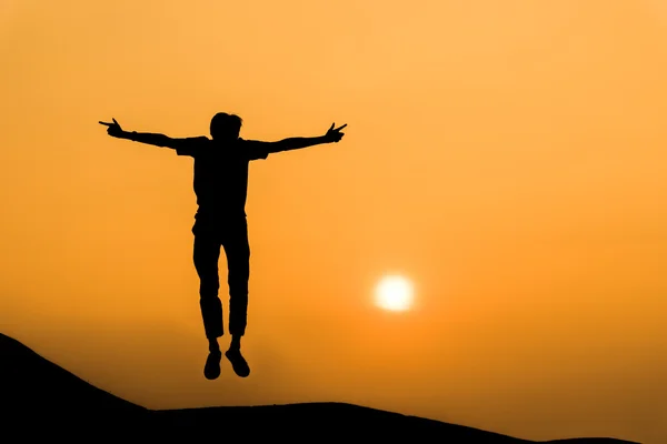 Silhouette of man in happy jump on orange sunset sky — Stock Photo, Image