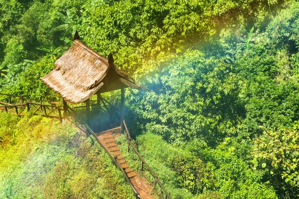 Cabaña de madera con arco iris de cascada en el bosque . — Foto de Stock