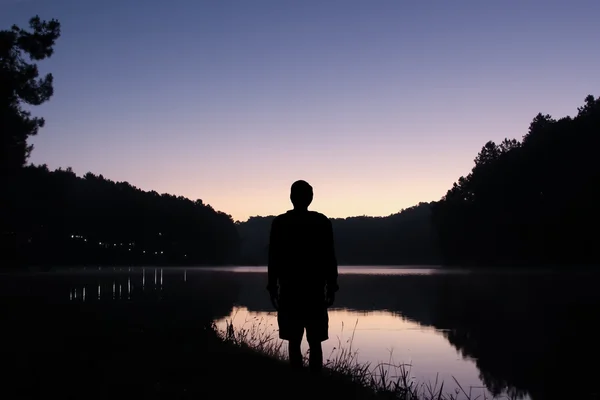Ο άνθρωπος στάση στη λίμνη με όμορφη Λυκόφως ουρανό με μωβ. — Φωτογραφία Αρχείου