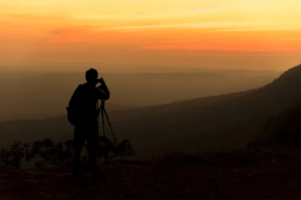 Silueta de viajero cuando está tomando fotografías en la montaña —  Fotos de Stock