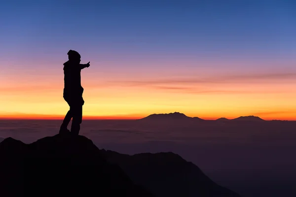 Silhouette des Mannes steht und Daumen hoch auf dem Gipfel des Berges — Stockfoto