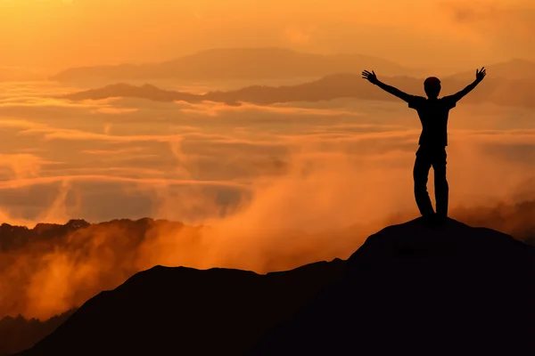 Sziluettjét turisztikai ember oldalpár kéz egy hegy tetején élvezni — Stock Fotó