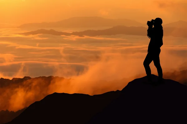 Silueta de mujeres está tomando alguna fotografía en la montaña al amanecer —  Fotos de Stock