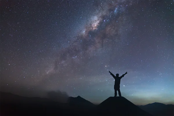 Ο άνθρωπος εξαπλώνεται χέρι πάνω σε λόφο και βλέποντας τον γαλαξία. — Φωτογραφία Αρχείου