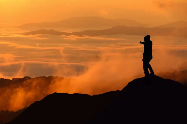 Silhouette eines Mannes, der auf dem Gipfel des Berges steht — Stockfoto