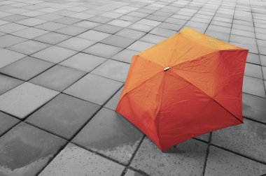 Yağmur sonrası ıslak zemin üzerinde kırmızı şemsiye.