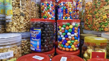 Renkli şeker topları, fıstık ve marketin rafında sergilenen plastik kavanozlarda çeşitli atıştırmalıklar. Kediri Endonezya, 14 Mart 2026