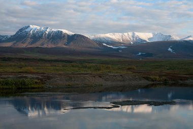 Karla kaplı dağlar sakin bir nehir yansıması.