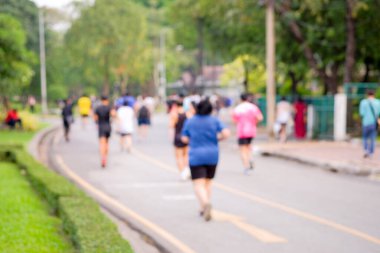İşten sonra kamu parkında koşan insanların dikiz görüntüsü ve bulanık görüntü odağı, bulanık odak arka planında koşmak sağlığın etkinliklerinden biridir.