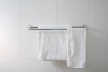 Kapalı banyo, iki beyaz havluyla beyaz fayans duvarında çelik korkuluklara asılmış iç ve ev dekorasyonu modern tarzda.