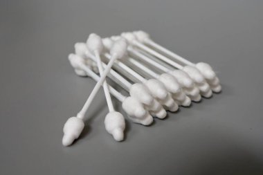 Gri arka planda tıpası olan pamuklu çubuklar. Bir çocuğun kulaklarını temizlemek. Pamuklu çubukları durduruculu yakın plan çek. Çocuk bakımı ve hijyen.