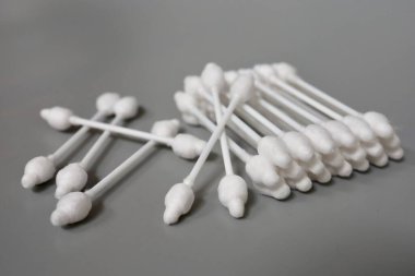 Gri arka planda tıpası olan pamuklu çubuklar. Bir çocuğun kulaklarını temizlemek. Pamuklu çubukları durduruculu yakın plan çek. Çocuk bakımı ve hijyen.
