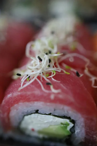 Ton balıklı suşi rulosu, krem peynirli ve mikroyeşillikli, yukarıdan kompozisyon. Makro fotoğraf, yüksek kaliteli fotoğraf..