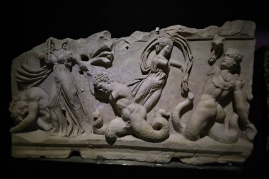 14-11-2025 İstanbul Türkiye: Arkeoloji müzesinde yılan kuyruklu mitolojik figürleri tasvir eden antik Roma yardım heykeli