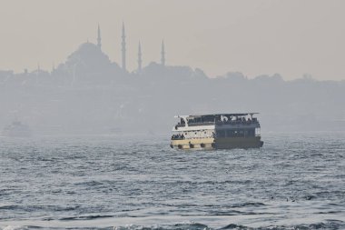 17-11-2025 İstanbul Türkiye: Arka planda tarihi camilerin siluetiyle İstanbul Boğazı 'nda seyahat eden yolcu gemisi