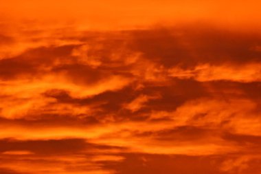 Gün batımı gökyüzünde, güneş kırmızı, bulutlar.