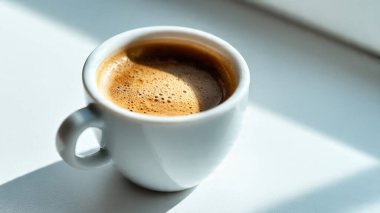 Beyaz arka planda kaşığı olan bir fincan kahve.