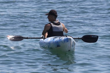 Sahilde sörf tahtası olan bir erkek sörfçü.