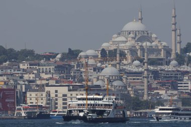 30-05-2024 İstanbul Türkiye: Arka planda yoğun kentsel ufuk çizgisi bulunan İstanbul Boğazı 'nda yolcu feribotu kalkıyor