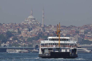 30-05-2024 İstanbul Türkiye: Arka planda yoğun kentsel ufuk çizgisi bulunan İstanbul Boğazı 'nda yolcu feribotu kalkıyor