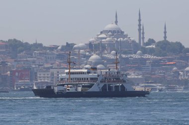 30-05-2024 İstanbul Türkiye: Arka planda cami kubbeleri ve minarelerle İstanbul Boğazı 'nda yolcu feribotu kalkıyor