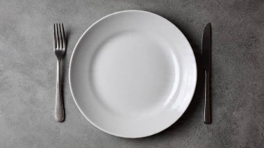 Siyah ahşap masada çatal bıçak takımı olan boş bir tabak.