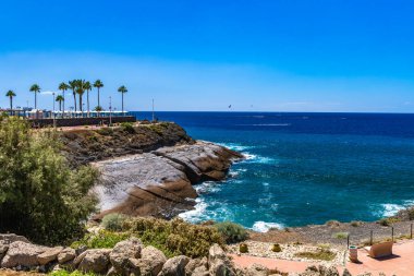 Kayalık sahil manzarası ve Tenerife 'nin güney kıyısındaki popüler tatil beldesi Playa del Duque bölgesindeki ünlü Casa del Duque. Tenerife adası ve okyanus bir yaz günü manzarası. 