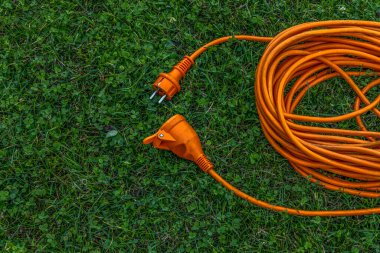 An electric extension cord lying on a green lawn in a garden, representing connection, harmony, and modern outdoor design. Concept of energy, unity, and sustainable living.