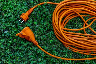 An electric extension cord lying on a green lawn in a garden, representing connection, harmony, and modern outdoor design. Concept of energy, unity, and sustainable living.