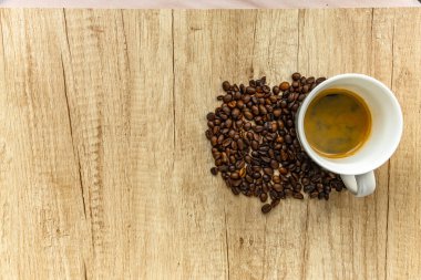 Top view of a coffee cup surrounded by spilled coffee beans on a wooden surface. Symbol of rising coffee prices, inflation, and global market trends in the coffee industry.