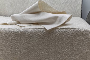 Close up of fitting a white boucl fabric cover on a corner sofa Concept of furniture renovation, upholstery work, and interior design craftsmanship.