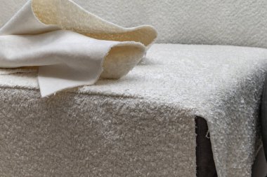 Close up of fitting a white boucl fabric cover on a corner sofa Concept of furniture renovation, upholstery work, and interior design craftsmanship.