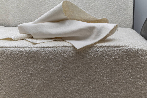 Close up of fitting a white boucl fabric cover on a corner sofa Concept of furniture renovation, upholstery work, and interior design craftsmanship.