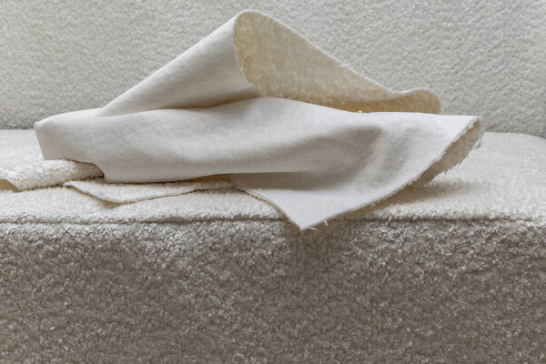 Close up of fitting a white boucl fabric cover on a corner sofa Concept of furniture renovation, upholstery work, and interior design craftsmanship.