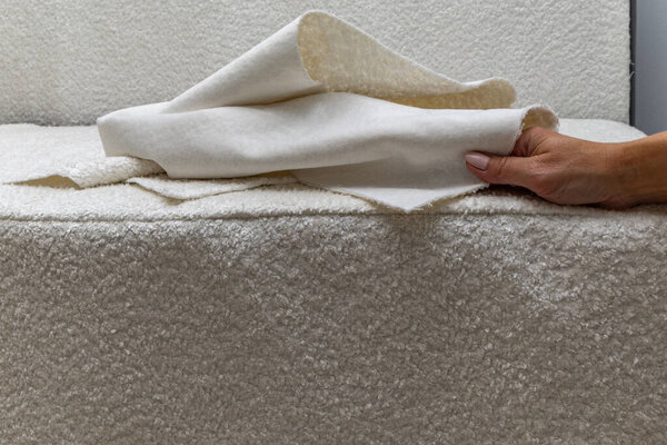 Close up of fitting a white boucl fabric cover on a corner sofa Concept of furniture renovation, upholstery work, and interior design craftsmanship.