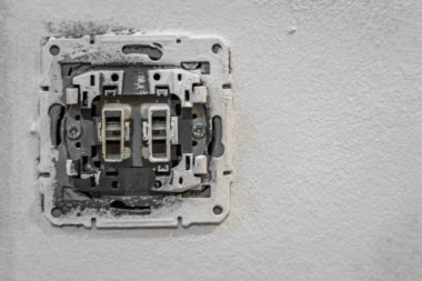 Ev tadilatı sırasında sökülmüş elektrik şalteri kablosuz olarak kapatılıyor. Elektrik onarımı, bakım, güç kurulumu ve DIY çalışması kavramı.