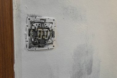 Ev tadilatı sırasında sökülmüş elektrik şalteri kablosuz olarak kapatılıyor. Elektrik onarımı, bakım, güç kurulumu ve DIY çalışması kavramı.