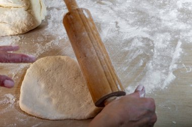 Hamuru elle yoğurmak ve mutfak tezgahında ahşap bir oklavayla yuvarlamak, mantarlı mantar ve etli geleneksel hamur işi, Noel tarifleri.