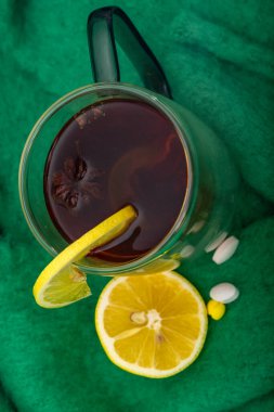 Soğuk algınlığı ve grip tedavisi için doğal yöntemler, alkollü çay, bal ve limon, ağrı kesiciler, yüksek ateşi düşüren ilaçlar, masada bir bardak sıcak içecek.