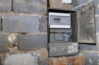 Bodrum duvarındaki eski elektrik sigorta kutusu, eski bir evde elektrik kesintisi, elektrik kesintisi, bozuk elektrik sistemi.