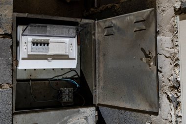 Bodrum duvarındaki eski elektrik sigorta kutusu, eski bir evde elektrik kesintisi, elektrik kesintisi, bozuk elektrik sistemi.